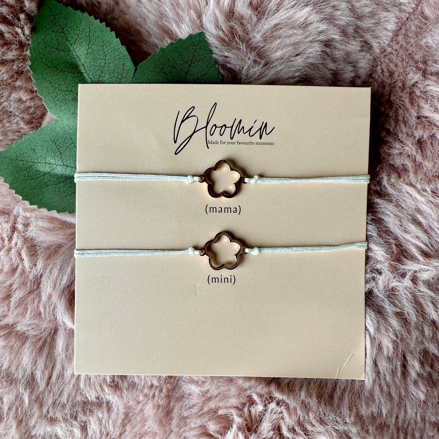 Pair of star-shaped bracelets on a 'Bloomin' branded card with leaves on a fluffy pink surface