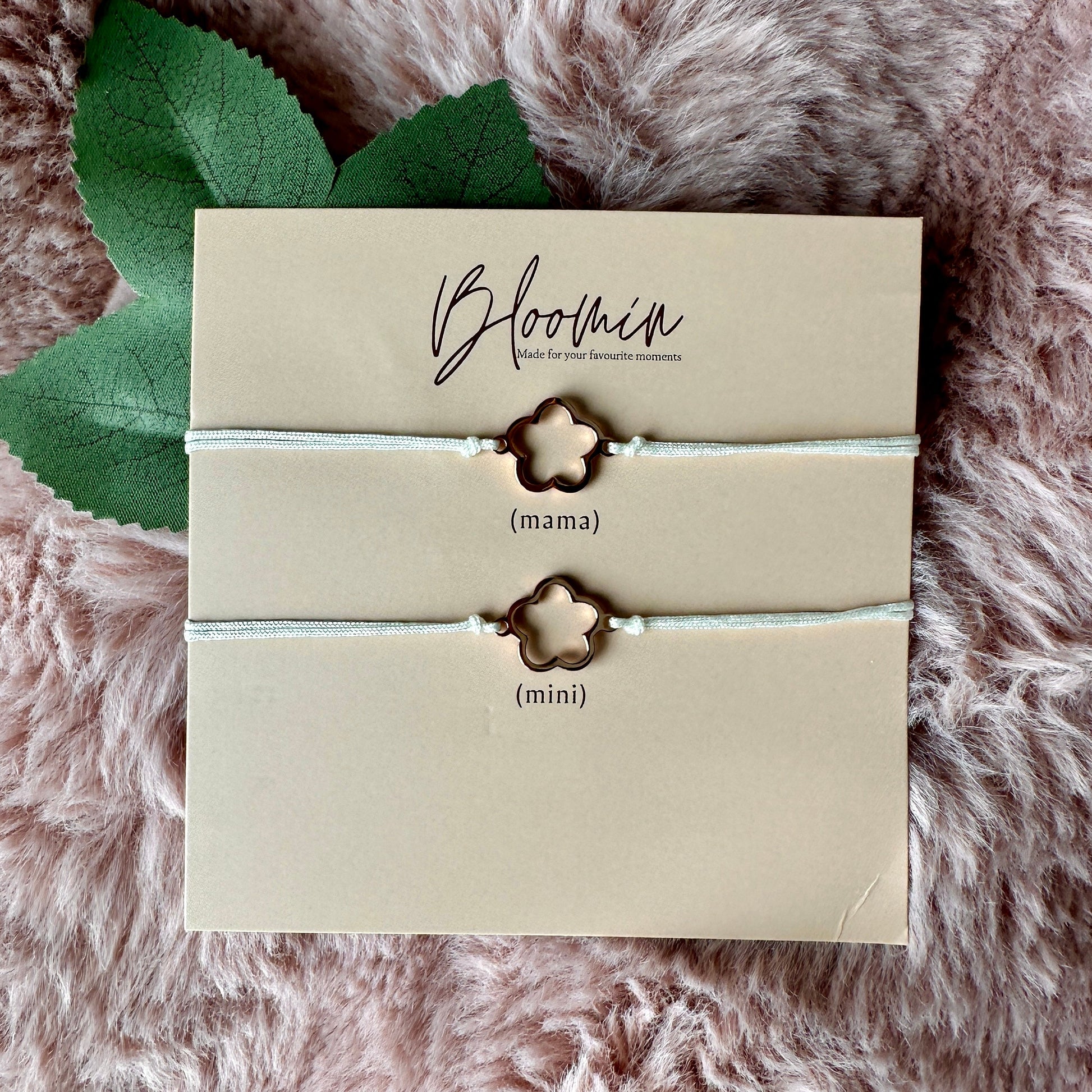 Pair of star-shaped bracelets on a 'Bloomin' branded card with leaves on a fluffy pink surface